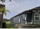 Side view of property with screen enclosure, complemented by a well-maintained lawn and a retaining wall at 4217 Balington Dr, Valrico, FL 33596