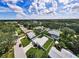 Aerial shot of the property with a lush green lawn and neighborhood with a pond at 717 Pinewood Dr, Dunedin, FL 34698
