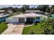 An aerial view of a well-maintained home with a lush green yard, a fenced-in backyard, and mature trees at 717 Pinewood Dr, Dunedin, FL 34698