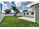 Backyard featuring a lush green lawn, palm trees, a cement patio, and a white fence at 717 Pinewood Dr, Dunedin, FL 34698