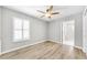 Bedroom featuring hardwood floors, a ceiling fan, a bright window with shutters, and a view into the bathroom at 717 Pinewood Dr, Dunedin, FL 34698