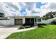 Charming home exterior with a well-manicured lawn, lovely landscaping, and an attached garage at 717 Pinewood Dr, Dunedin, FL 34698