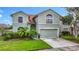 Charming two-story home with a two-car garage, lush lawn, tropical landscaping, and neutral color scheme at 9707 Kings Canyon Pl, Tampa, FL 33634