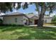 Charming single-story home with well-manicured lawn, mature trees, and a welcoming red front door at 1137 Pristine Pl, Lutz, FL 33549