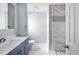 This bathroom features a blue vanity, marble floors, and a shower with unique stone and tile accents at 116 Hermes Rd, Venice, FL 34293