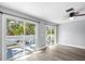 A bright living space features wood-look flooring and access to an outdoor deck with views of tropical trees at 116 Hermes Rd, Venice, FL 34293