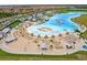 Aerial shot of the beach entry to the community pool, with many chairs and umbrellas at 17071 Oval Rum Dr, Wimauma, FL 33598