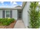 Close-up of the front entry door with gray door, window and landscaped garden at 17071 Oval Rum Dr, Wimauma, FL 33598