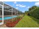 Landscaped backyard showcasing the screened pool, mulch beds and lush greenery at 2567 Frisco Dr, Clearwater, FL 33761