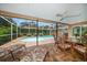 Inviting covered pool area with brick-paver patio, ceiling fan, stylish furniture, and screened enclosure at 2567 Frisco Dr, Clearwater, FL 33761