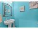 Stylish powder room with a pedestal sink, bright blue walls, and modern decor at 5955 Caldera Ridge Dr, Lithia, FL 33547