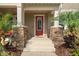 Close up of front entrance with stone columns and bright red door at 5955 Caldera Ridge Dr, Lithia, FL 33547