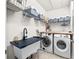 Functional laundry room with storage shelves, a utility sink, and front-loading washer and dryer at 5955 Caldera Ridge Dr, Lithia, FL 33547