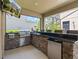 An outdoor kitchen on the screened patio has a built in gas grill, sink, mini-fridge, and breakfast bar for entertaining at 5955 Caldera Ridge Dr, Lithia, FL 33547