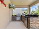 Outdoor kitchen on the screened patio with built in gas grill, sink, mini-fridge, and breakfast bar is perfect for outdoor living at 5955 Caldera Ridge Dr, Lithia, FL 33547
