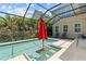Relaxing screened-in pool with a tranquil view, featuring a vibrant red umbrella for shade and privacy at 5955 Caldera Ridge Dr, Lithia, FL 33547