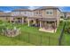 Spacious backyard featuring a covered patio, pergola with swings, and cozy fire pit seating area at 6555 Kenava Loop, Palmetto, FL 34221