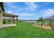 Large backyard featuring a covered patio with swings, a fire pit, and pond views at 6555 Kenava Loop, Palmetto, FL 34221