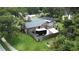 Aerial view of a home with a screened pool, lush greenery, and a fenced yard at 713 Rustic Oaks Dr, Palm Harbor, FL 34684