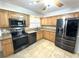 Modern kitchen with stainless steel appliances, granite countertops, tile flooring, and natural wood cabinets at 713 Rustic Oaks Dr, Palm Harbor, FL 34684