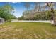 Expansive backyard featuring green grass, mature trees, white fencing, and a screened-in patio at 7607 New York Ave, Hudson, FL 34667