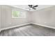 Well-lit bedroom showcases a ceiling fan, window, and durable gray wood laminate flooring at 7607 New York Ave, Hudson, FL 34667