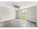 Bedroom with gray wood-look flooring, neutral paint, ceiling fan, and a large window at 7607 New York Ave, Hudson, FL 34667