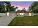 Well-lit single-story home featuring a stone facade, attached garage, and a spacious driveway at dusk at 7607 New York Ave, Hudson, FL 34667
