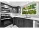 Close-up of modern kitchen showcasing stainless steel appliances, sleek cabinetry, and a window view at 7607 New York Ave, Hudson, FL 34667