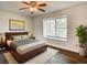 Bedroom with wood floors, ceiling fan, and window view of lush greenery at 9027 Pebble Creek Dr, Tampa, FL 33647