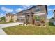 Two-story home featuring a three-car garage, stone accents, and beautifully landscaped front yard at 9456 Channing Hill Dr, Sun City Center, FL 33573