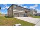 Two-story home featuring a three-car garage, stone accents, and a large front yard at 9456 Channing Hill Dr, Sun City Center, FL 33573