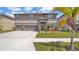 Two-story home featuring a three-car garage, stone accents, and beautifully landscaped front yard at 9456 Channing Hill Dr, Sun City Center, FL 33573