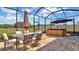 Screened-in patio with brick flooring, outdoor dining set, umbrella, and spa at 9456 Channing Hill Dr, Sun City Center, FL 33573