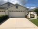Beige garage and concrete driveway of a one-story home, with white trim and updated windows at 11439 Cambray Creek Loop, Riverview, FL 33579