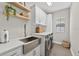 Bright laundry room features modern washer and dryer, stainless steel farmhouse sink, and white cabinetry for ample storage at 12928 Twin Bridges Dr, Riverview, FL 33579