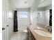 Neutral bathroom with wooden vanity, framed mirror, shower-tub combo, and white tile at 1725 Bondurant Way, Brandon, FL 33511