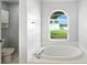 Bathroom with large soaking tub, tiled surround, and a window overlooking the landscaped backyard at 1725 Bondurant Way, Brandon, FL 33511