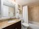 Bathroom featuring a granite countertop, decorative mirror, and shower with neutral tile surround at 20002 Gulf Blvd # 2803, Indian Shores, FL 33785