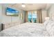 Bedroom with light blue walls, a ceiling fan, TV, and ocean view through sliding glass doors at 20002 Gulf Blvd # 2803, Indian Shores, FL 33785