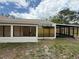 A sunroom with large windows adjoins a black-framed screened-in porch in a spacious backyard at 23220 Shining Star Dr, Land O Lakes, FL 34639