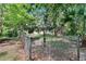 View of backyard through chain link fence with lush landscaping and mature trees at 3102 E Trapnell Rd, Plant City, FL 33566