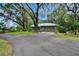 Home exterior featuring a metal roof, lush landscaping, and a long driveway at 3102 E Trapnell Rd, Plant City, FL 33566