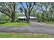 Home exterior with a metal roof, mature trees, and long driveway at 3102 E Trapnell Rd, Plant City, FL 33566