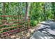 Red metal gate and tree-lined driveway providing privacy to the property at 3102 E Trapnell Rd, Plant City, FL 33566