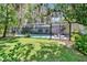 Backyard view of a screened pool enclosure with outdoor seating and lush landscaping at 3102 E Trapnell Rd, Plant City, FL 33566