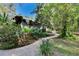 Landscaped side yard featuring a curved sidewalk, mature plantings, and partial fencing at 3102 E Trapnell Rd, Plant City, FL 33566