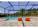 Screened-in pool with stylish lounge chairs, landscaped surroundings, and a clear blue sky at 4372 Night Star Trl, Odessa, FL 33556