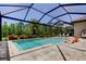 Enclosed pool featuring orange lounge chairs, screened-in enclosure, and lush green landscaping at 4372 Night Star Trl, Odessa, FL 33556