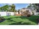 Well-maintained backyard with artificial turf, a wooden deck, white fencing, and mature tropical landscaping at 500 62Nd S St, St Petersburg, FL 33707